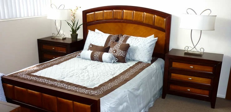 A bedroom with a bed and two nightstands at the Plymouth apartments.