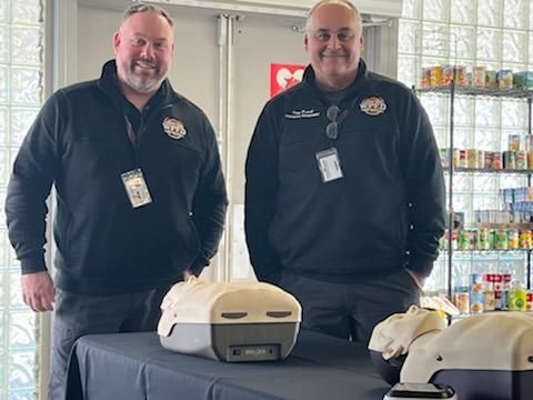 Ryan Fisher and Anthony Braish smile for a picture with CPR dummies.