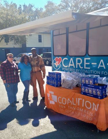 Three people stand next to a table and smile for a picture.