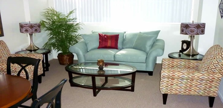 A styled living room with a couch, two chairs and a coffee table at the Plymouth apartments.