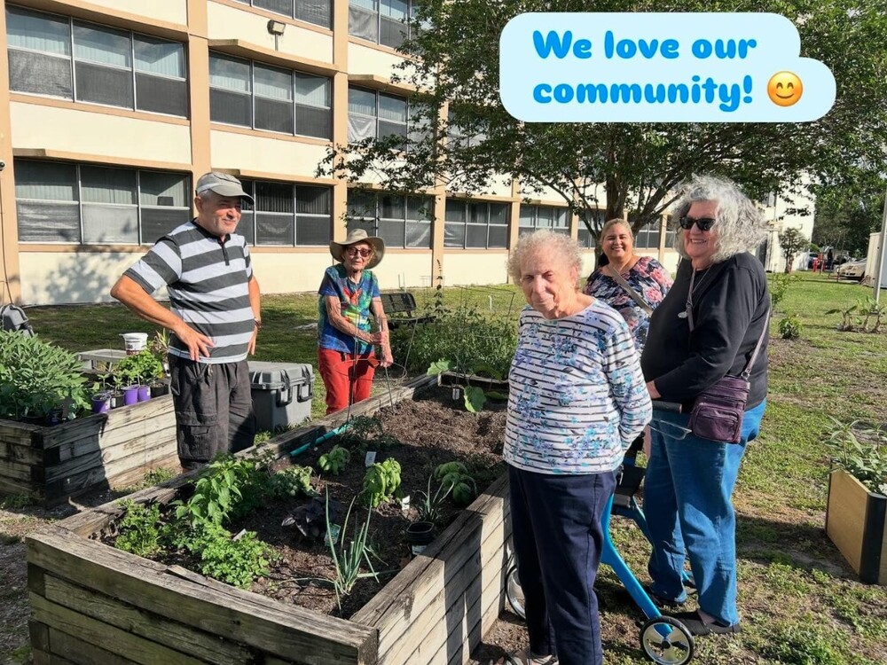 Five people smile next to a garden bed. We love our community!