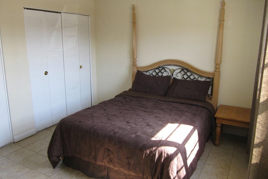 A bed sits in middle of an empty room in a one-bedroom rental.