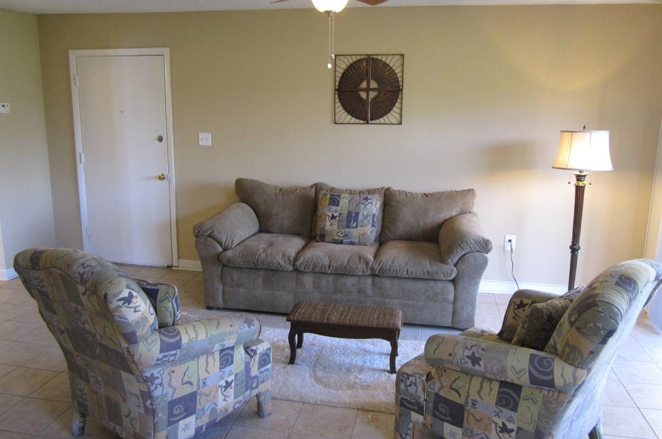 A living room with one couch and 2 chairs that are facing each other in the one-bedroom rental.
