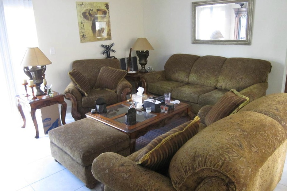A couch, loveseat, and chair are arranged around the coffee table in the living room of this two-bedroom rental.