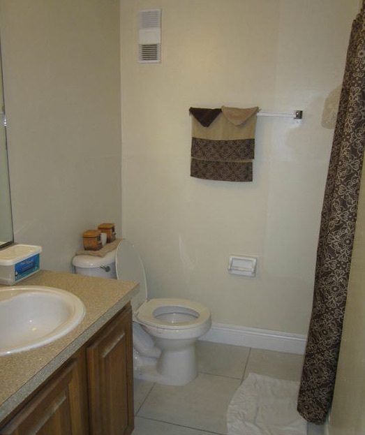 The shower, hand towel rack, toilet, and vanity in the other bathroom of the three-bedroom rental.