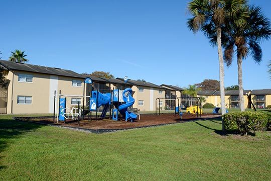 The playground is mulched and surrounded by a small black fence.