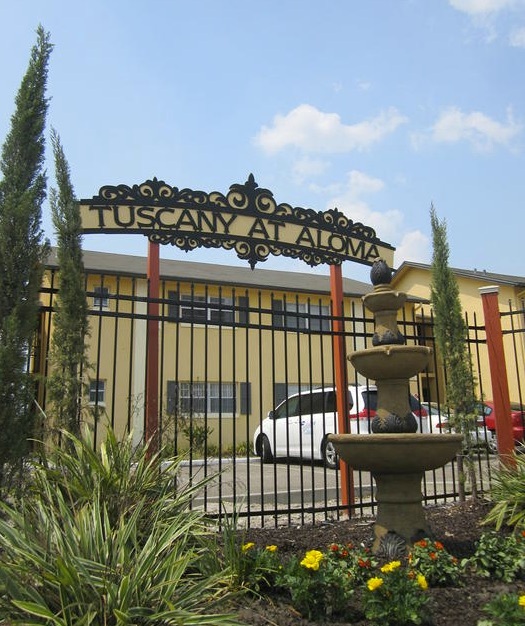 An iron fence and a sign that says Tuscany At Aloma at the top. 