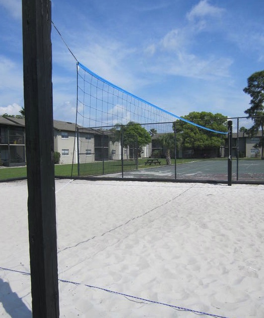 A volleyball net sits next to a tennis court outside of the Tuscany at Aloma rentals. 