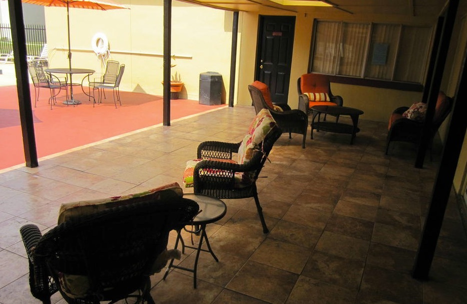 Tables and chairs are arranged in the shade near the pool for residents to use. 