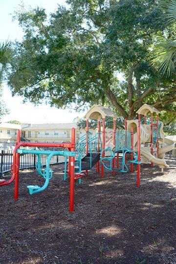 The playground equipment is enclosed by a black fence. 