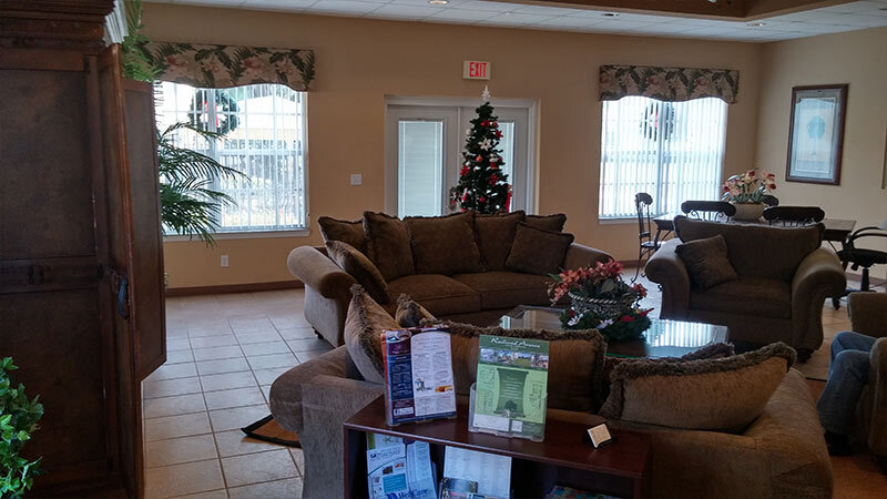 A shared community space during Christmas time with one couch facing two chairs and a Christmas tree in the background.