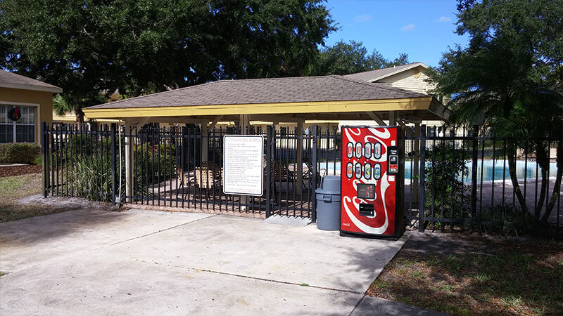 A coke machine sits to the right of the pool gate. 