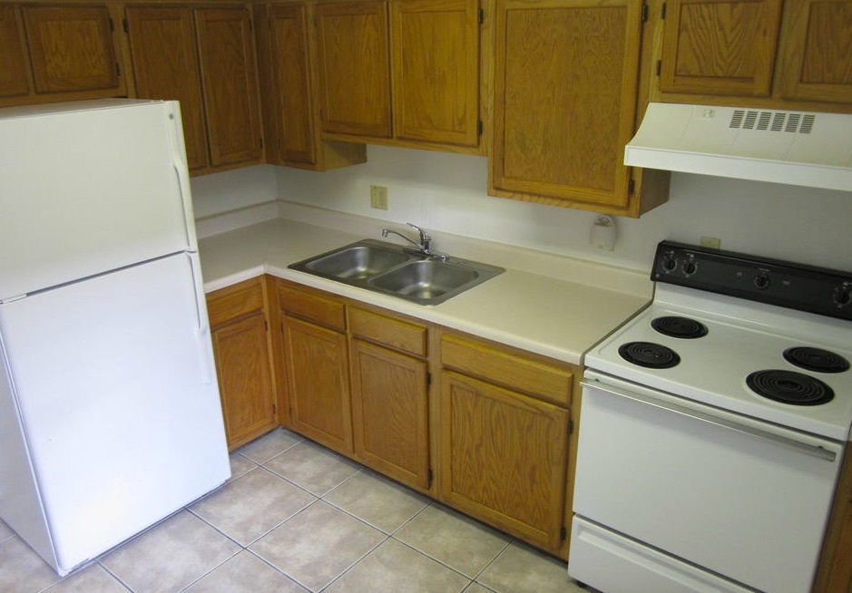 An empty and clean kitchen with a refrigerator, sink and stove in the three-bedroom rental.