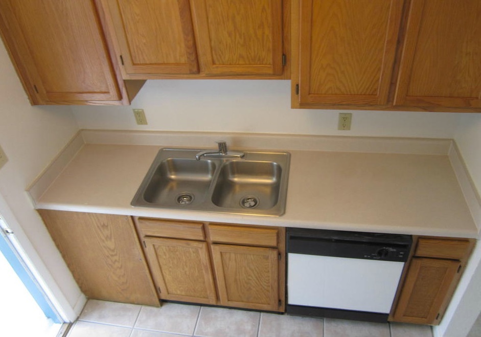 A clean and empty double stainless steel sink and a dishwasher are in one counter in the kitchen of the two-bedroom rental.