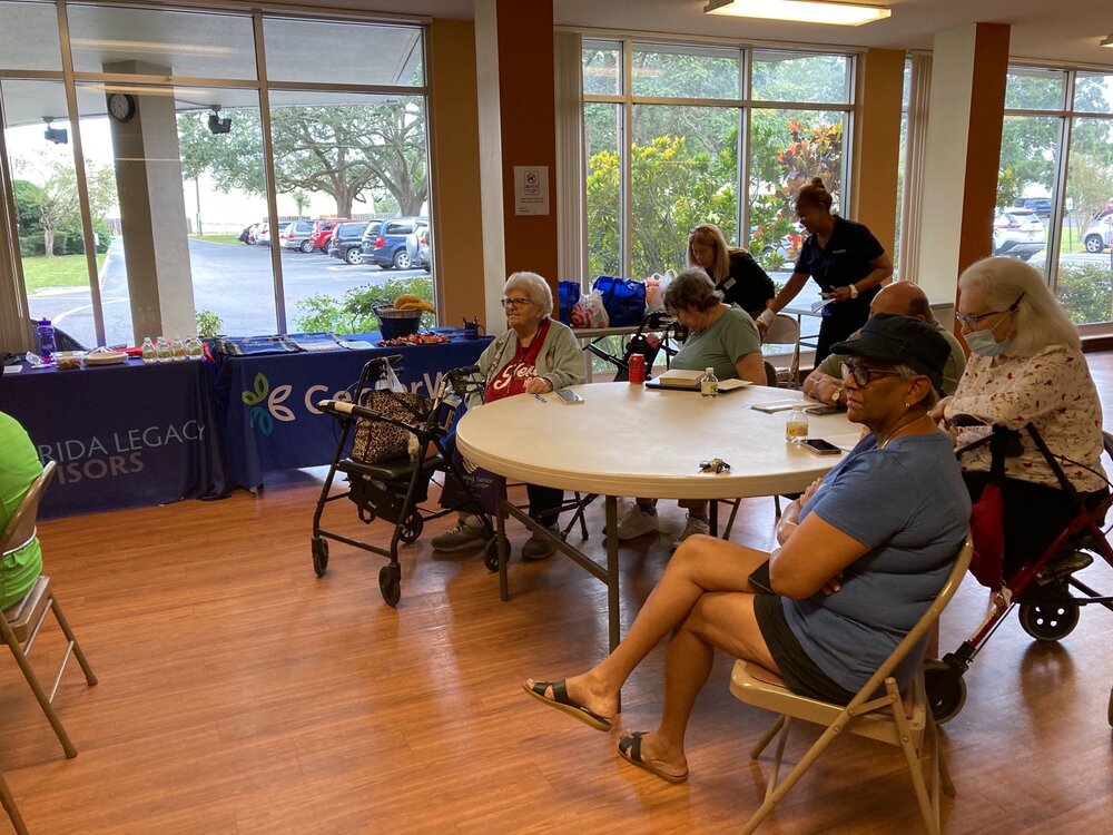 Five senior citizens sitting at table listening to speaker