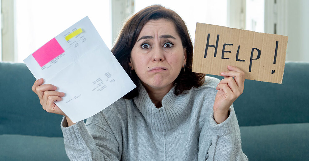 A woman holding a bill in one hand and a sign that reads HELP! in the other hand.