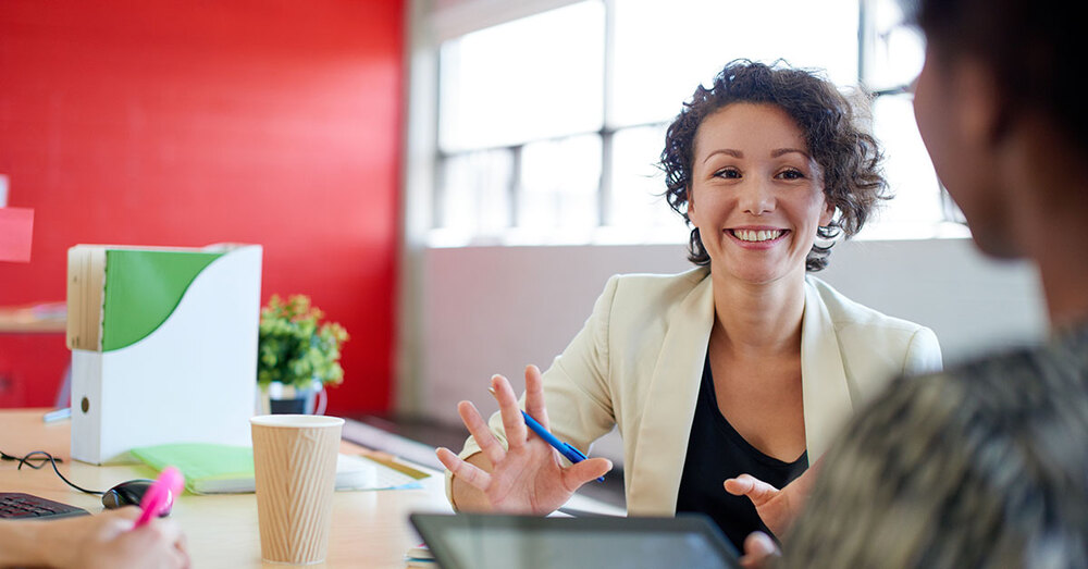 A woman smiles and gestures with her hands as she talks to someone else. 