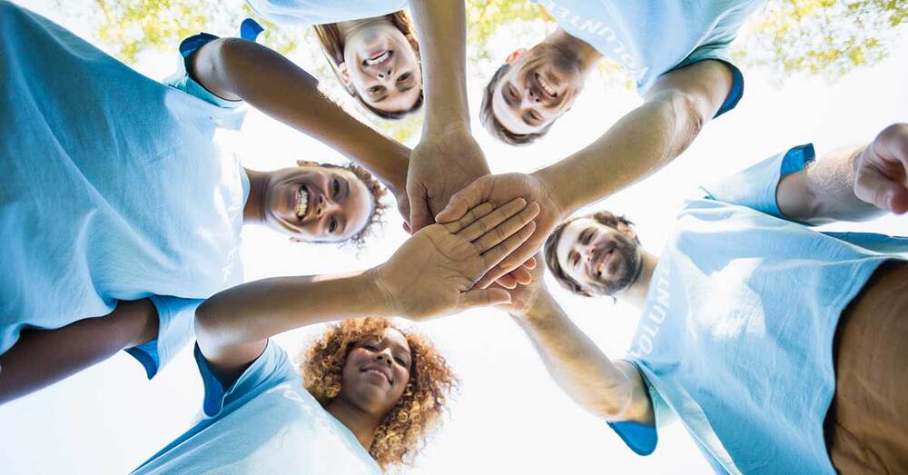 A group of individuals standing in a circle doing a huddle.