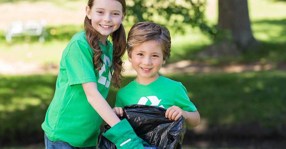 Two children wearing recycle shirts, helping with errands.