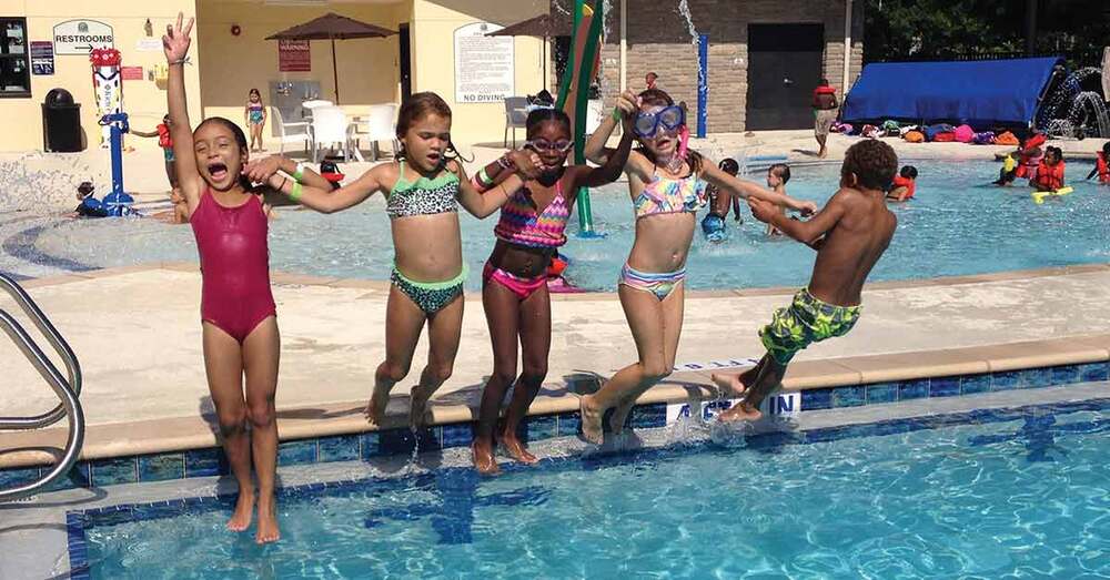 Five children jumping in a swimming pool simultaneously.