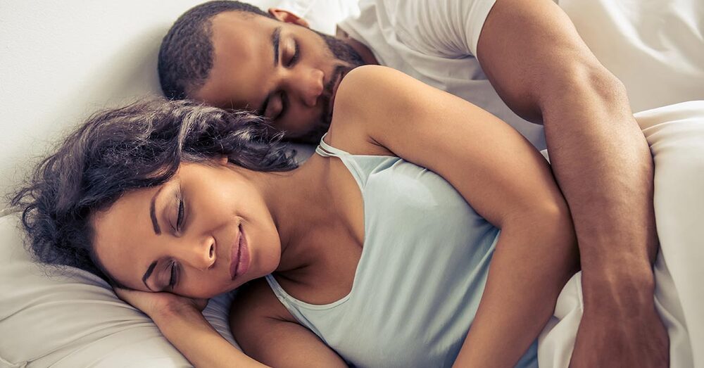 Two individuals in bed sleeping.