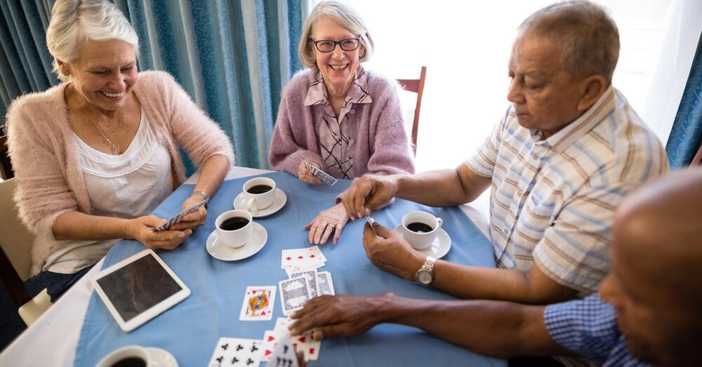 A group of seniors sitting around a table playing cards.