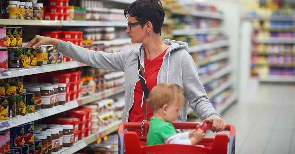 A woman and child in a grocery store shopping for food.