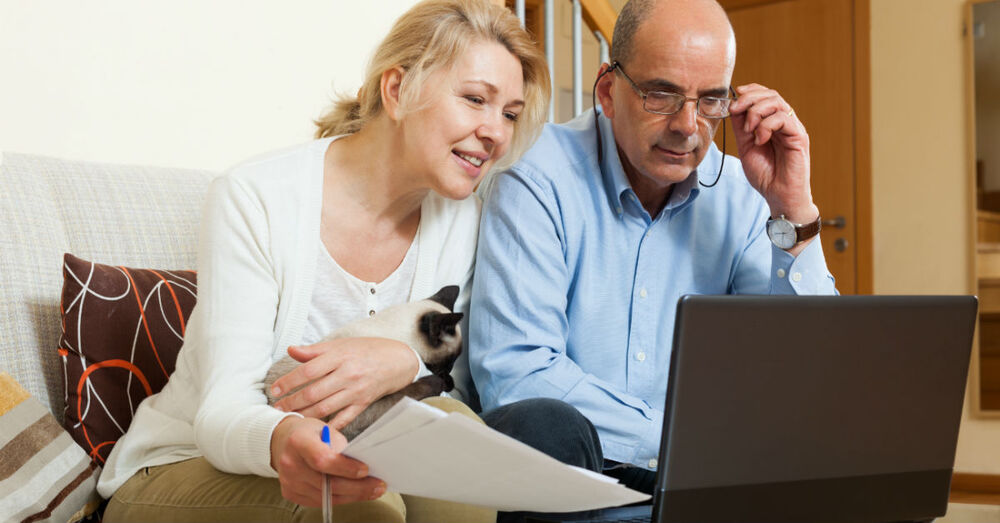 Two individuals sitting together looking at a laptop screen.