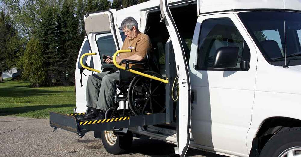 An individual getting out of a wheel chair accessible vehicle.
