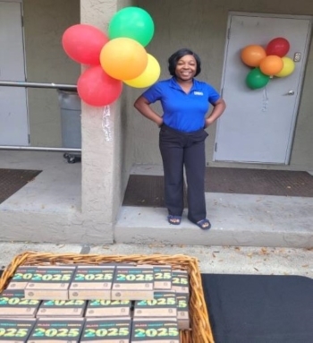 Lady standing outside by some bundles of balloons and a display of items for 2025.