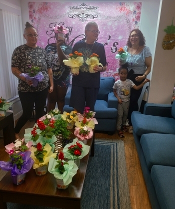 A group of ladies and a clild surrounded by and holding flowers.