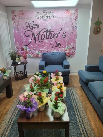 Mothers Day Celebration Sign with a table full of flowers.