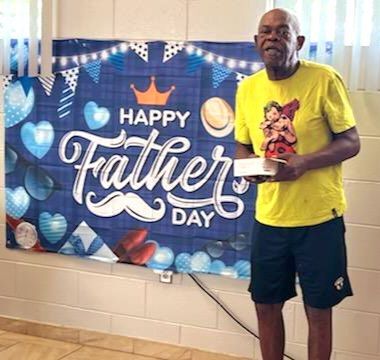A man standing next to a sign that says Happy Father's Day.