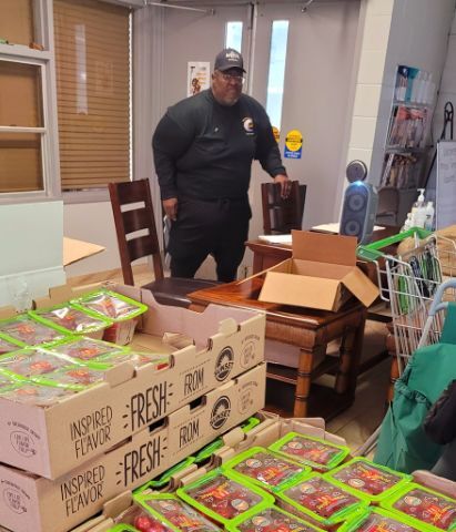 A man standing in a room with boxes of tomatoes.