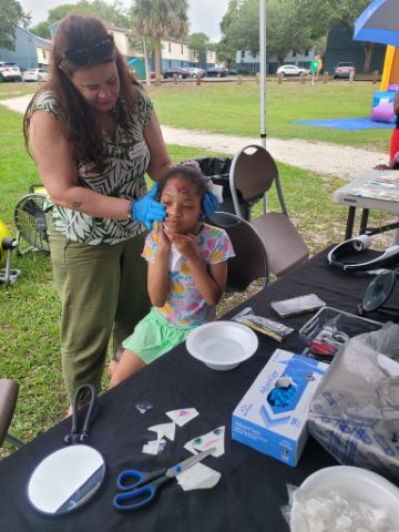 A young girl getting a temporary tattoo put on.