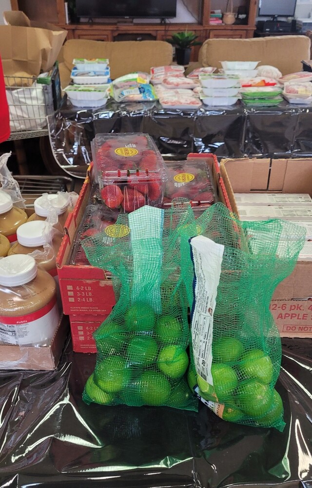 A bag of limes next a box of applesauce on a table.