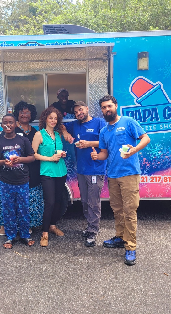 A group of five people standing and smiling outside Papa G's Freeze shop food truck.