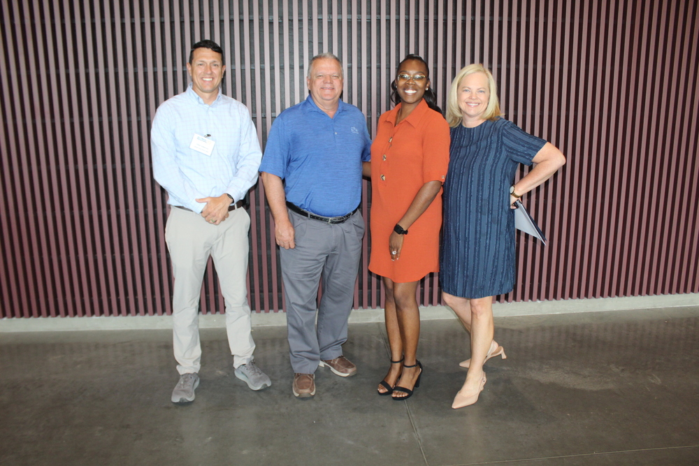 Four people stand and smile for a photo.