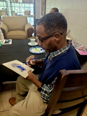 Man painting while sitting at a table. 
