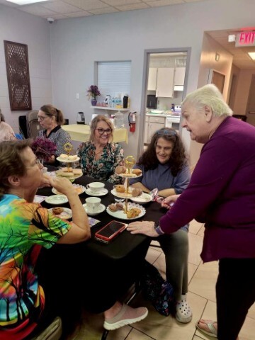 Women enjoying tea at a table with cookies, tea and cakes. 