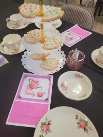 Tea setting with cups, saucers, and a tray of cookies. 