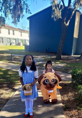 Two children, one dressed as Dorothy in the Wizard of Oz, and another as a dog. 