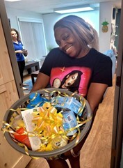 Woman holding a basket of food with a big ribbon on it. 
