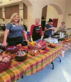 Line of people behind tables covered in snacks.