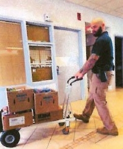 Man pushing boxes on a dolly.