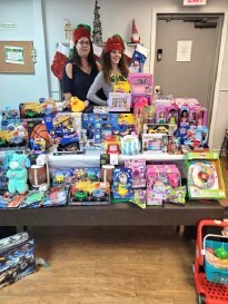 Two women standing behind a table full of toys.