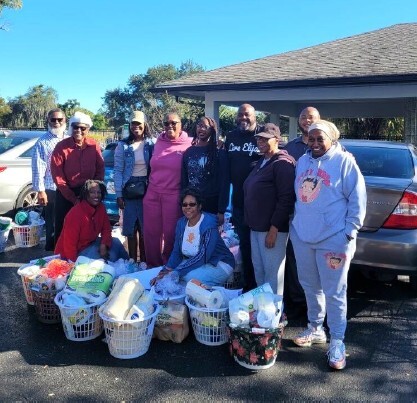 A group of people standing around holiday gift baskets in a parkinglot.