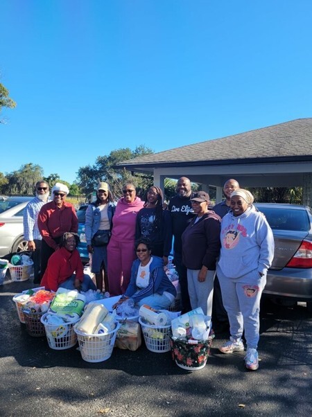 A group of people standing around holiday gift baskets in a parking lot.