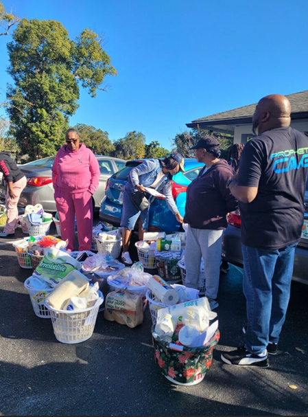 People standing in a parking lot with gift baskets.