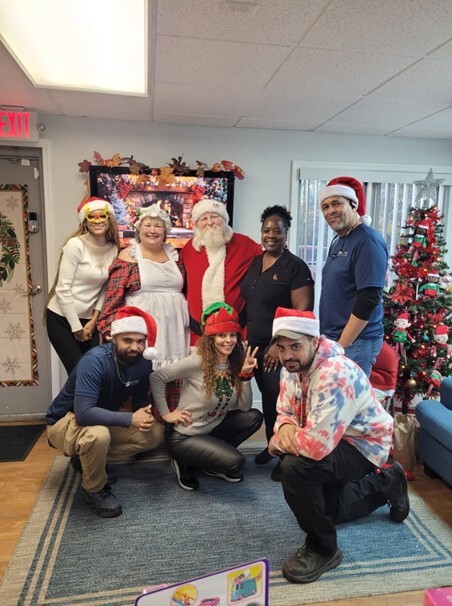 Six people standing and smiling for a photo with Santa and Mrs. Clause.